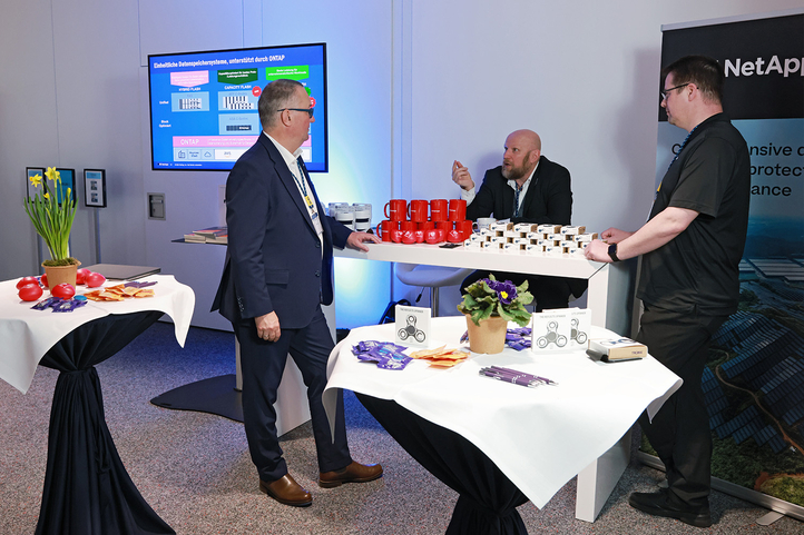 Zwei Männer im Gespräch an einem Messestand, umgeben von Produktinformationen von SHD.