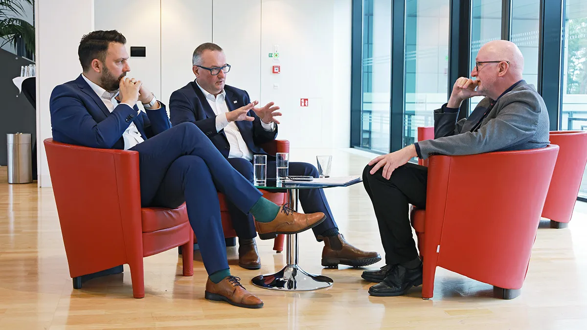 Drei Geschäftsleute diskutieren strategische IT-Lösungen in einer modernen Büroumgebung von SHD.