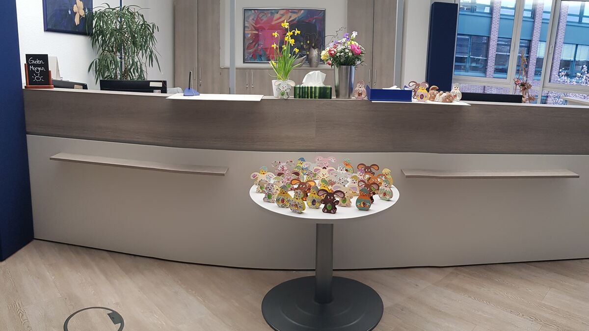 Schreibtisch mit bunten, dekorativen Hasenfiguren im Empfangsbereich von SHD.