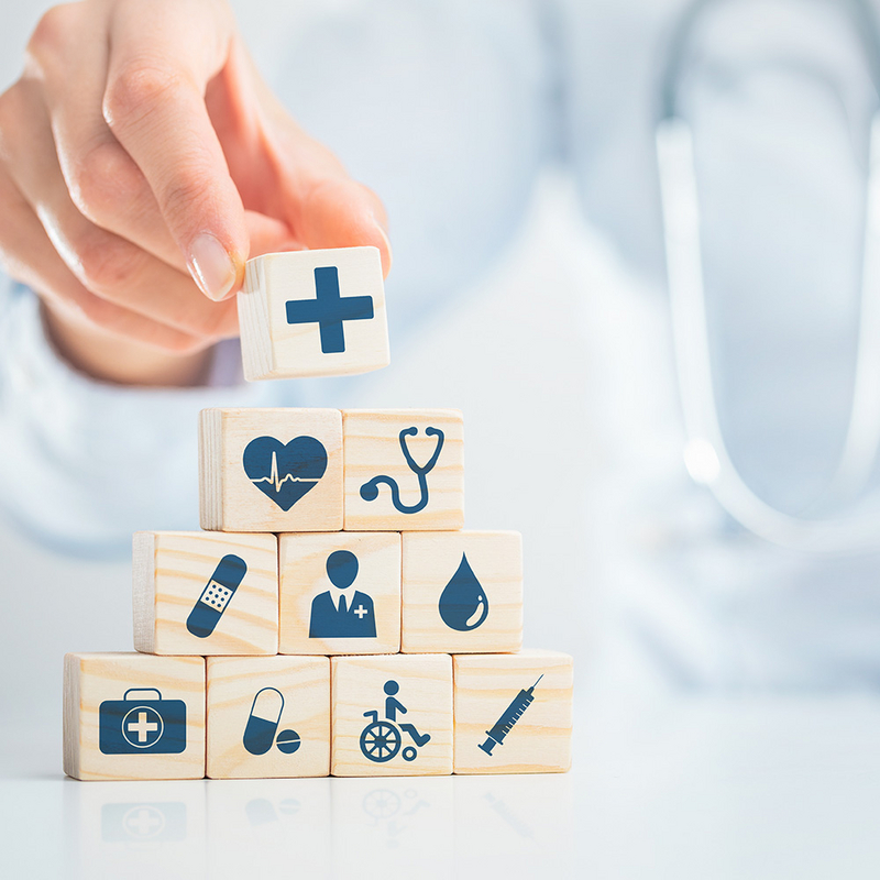 Holzwürfel mit medizinischen Symbolen werden gestapelt, um Gesundheitsdienste von SHD zu präsentieren.