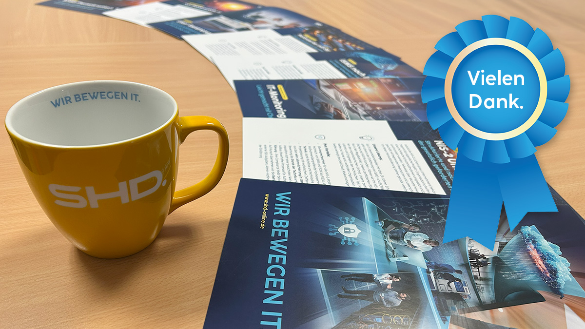 Eine Reihe von SHD-Flyern zu verschiedenen IT-Themen liegen in einer Reihe, daneben eine Tasse mit SHD Logo und eine Plakette mit den Worten "Vielen Dank."