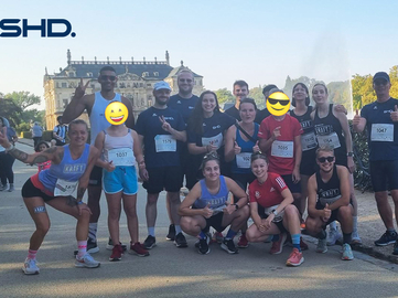 SHD-Team posiert nach dem Lauf vor einem historischen Gebäude in einem Park.