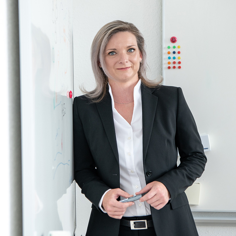 Eine professionell gekleidete SHD Fachexpertin präsentiert IT-Lösungen vor einem Whiteboard.