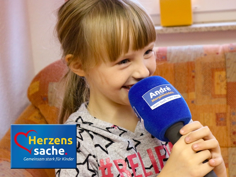 Glückliches Mädchen mit großem Mikrofon, SHD unterstützt das Projekt Herzenssache - Gemeinsam stark für Kinder.