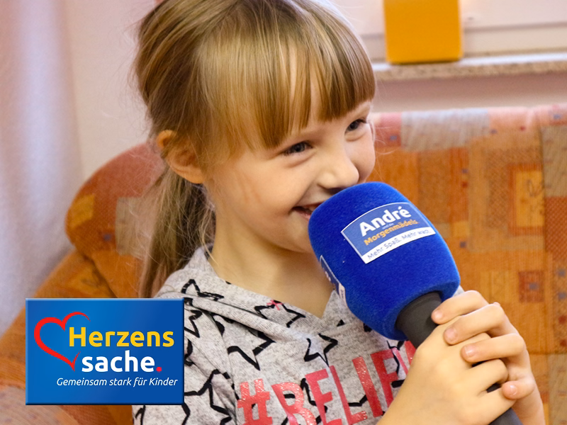 Glückliches Mädchen mit großem Mikrofon, SHD unterstützt das Projekt Herzenssache - Gemeinsam stark für Kinder.