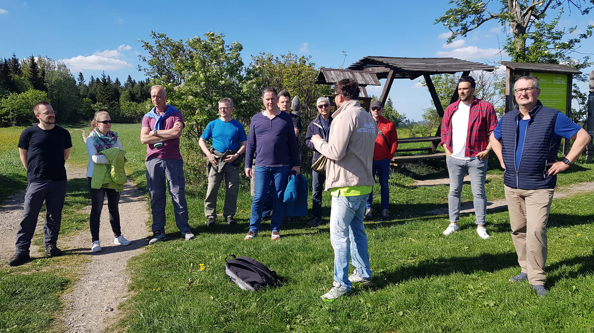Eine Gruppe von Menschen hört einem Redner im Freien im Grünen zu, ideal für Teambuilding-Events bei SHD.