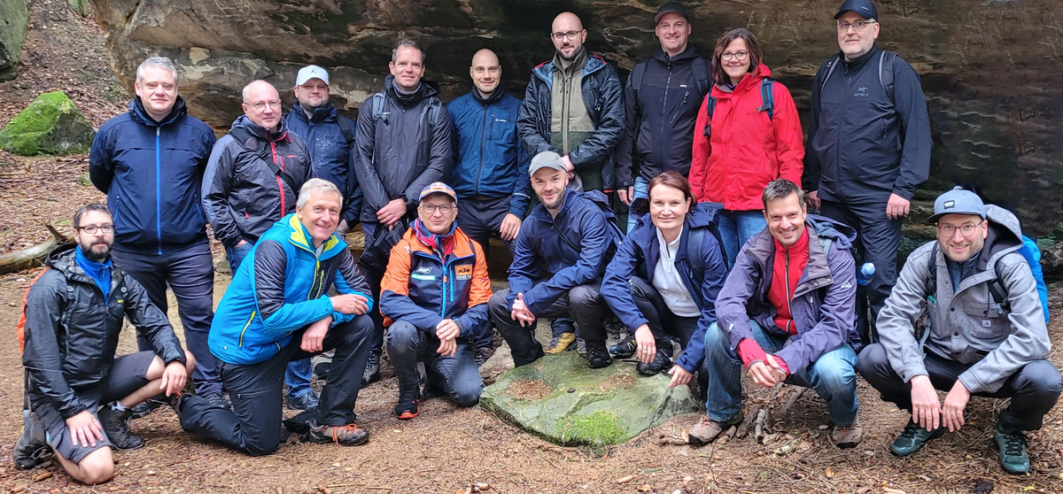 Eine Gruppe von SHD-Mitarbeitern posiert lächelnd im Wald, umgeben von Bäumen und Felsen.