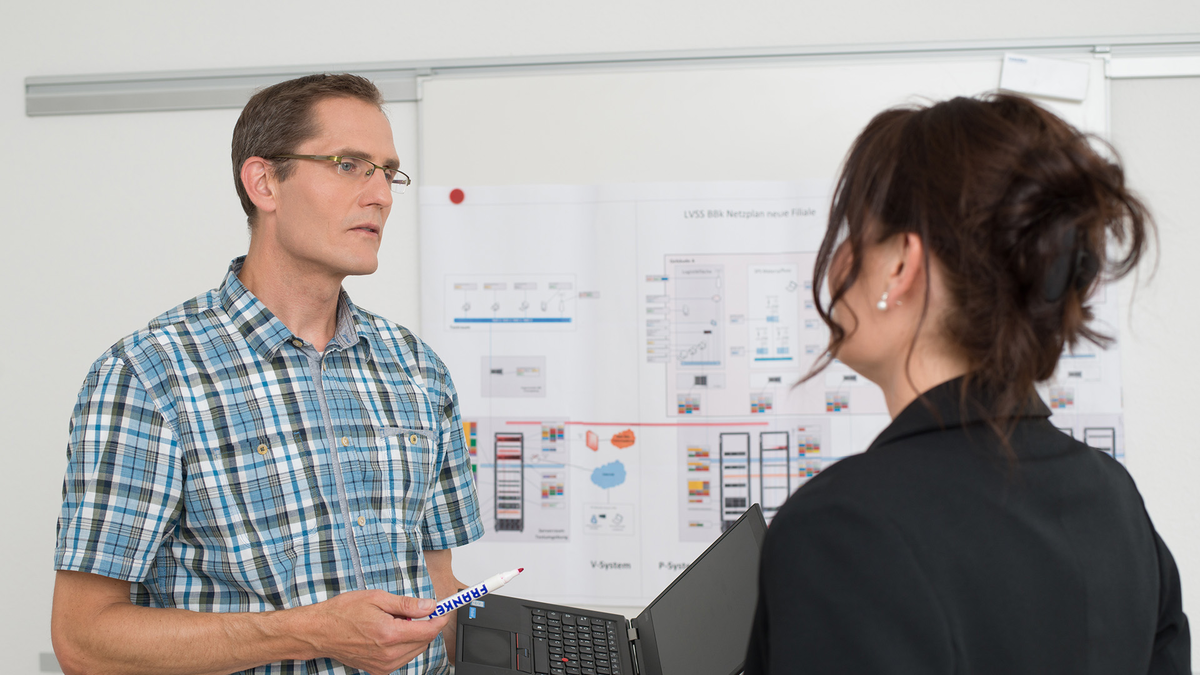 Zwei Fachleute diskutieren vor einem Diagramm über IT-Lösungen von SHD.