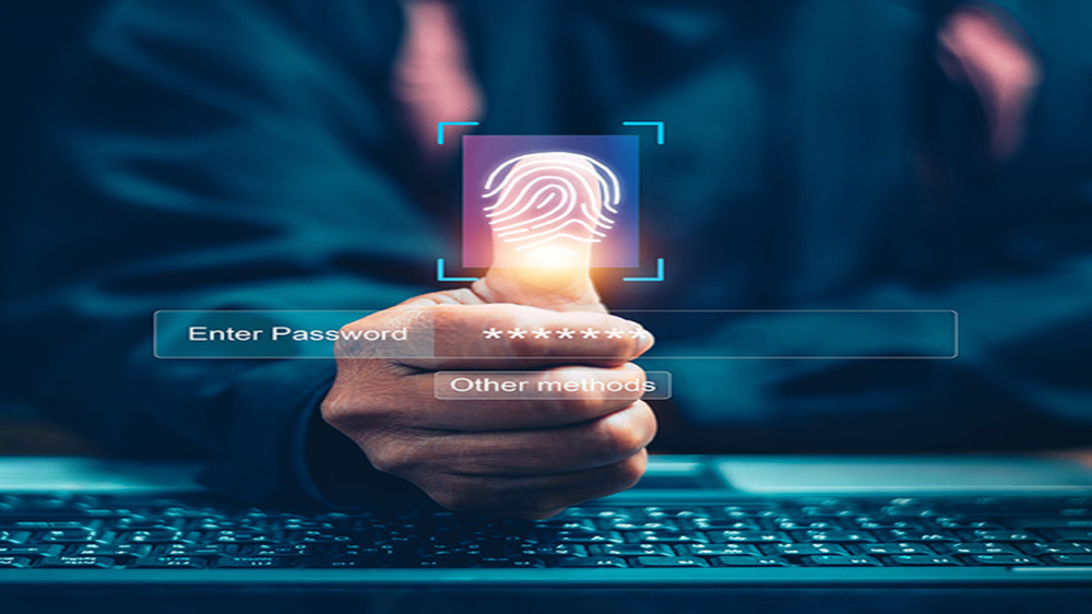 Ein Mann am Laptop hält seinen Daumen in die Kamera, sein Fingerabdruck als Symbol für sicheren Zugang ist grafisch hervorgehoben.