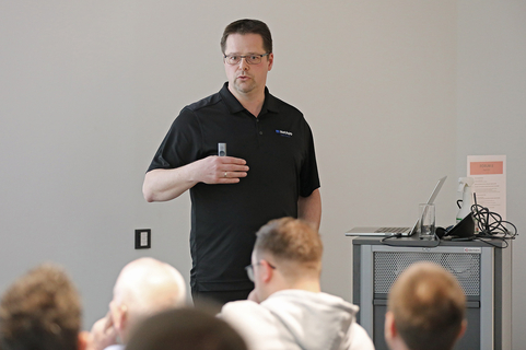 Ein Sprecher präsentiert IT-Lösungen von SHD vor einem interessierten Publikum in einem modernen Raum.