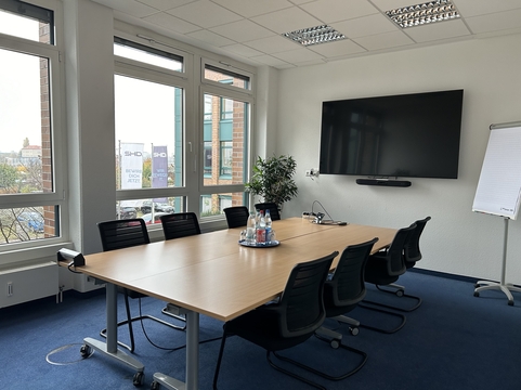 Modernes Besprechungszimmer mit einem großen Tisch, Sitzmöglichkeiten und digitaler Präsentationstechnologie von SHD.