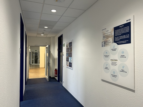 Ein gut beleuchteter Flur mit Wänden des IT-Dienstleisters SHD in Dresden, versehen mit Informationsgrafiken.