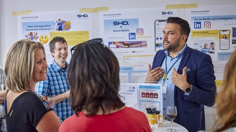 Gruppengespräch über Corporate Influencer, geleitet von einem SHD-Mitarbeiter, umgeben von Informationsplakaten.