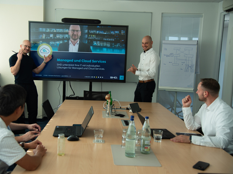 Teammeeting bei SHD, Präsentation von Managed und Cloud Services auf großem Bildschirm.