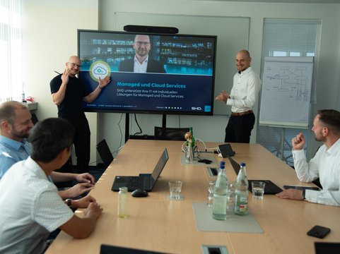 Teammeeting bei SHD, Präsentation von Managed und Cloud Services auf großem Bildschirm.