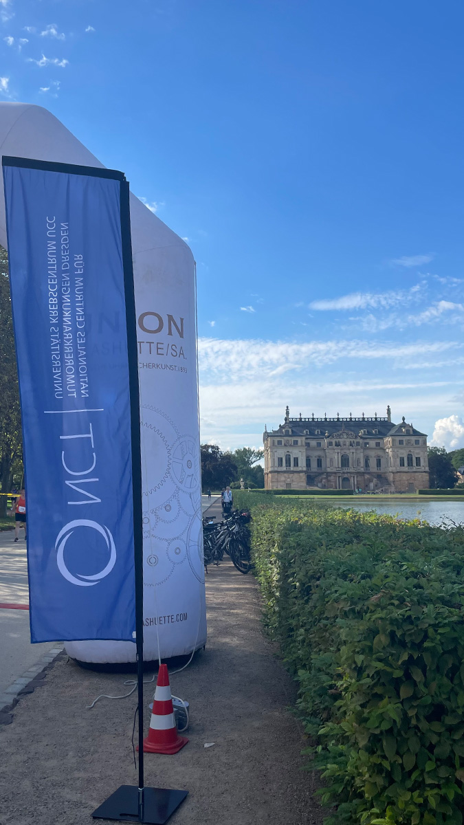 Flagge vom Nationalen Centrum für Tumorerkrankungen Dresden, dahinter das Palais Großer Garten.