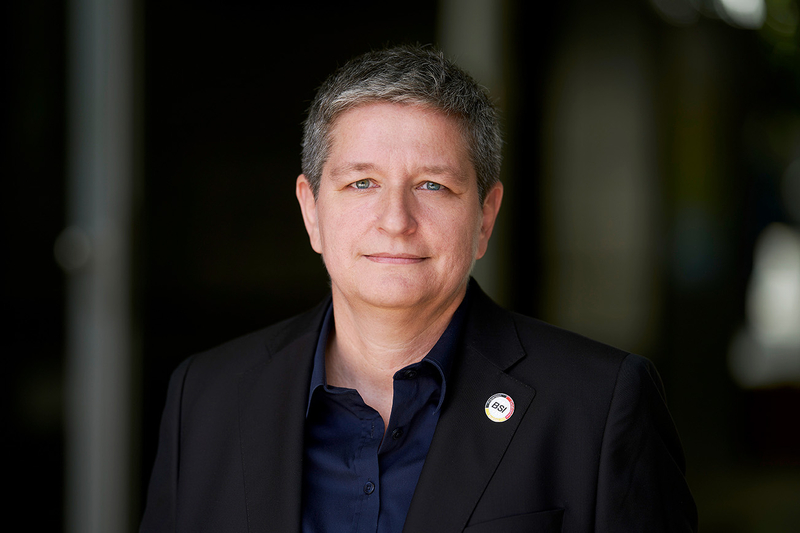 Professionelle Person im Anzug lächelt, präsentiert sich in einem modernen Umfeld für IT-Dienstleistungen von SHD.