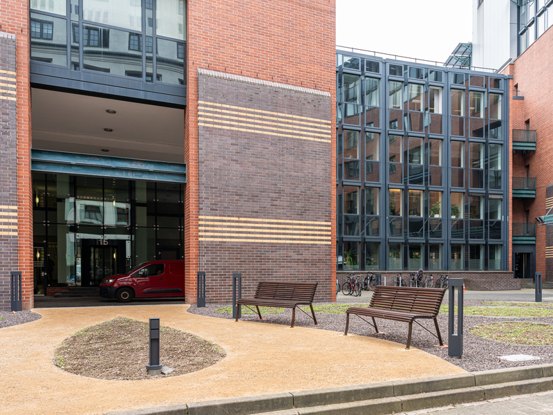Außenaufnahme der Leipziger Geschäftsstelle mit sonnigem Park und Bänken auf der Prager Straße.