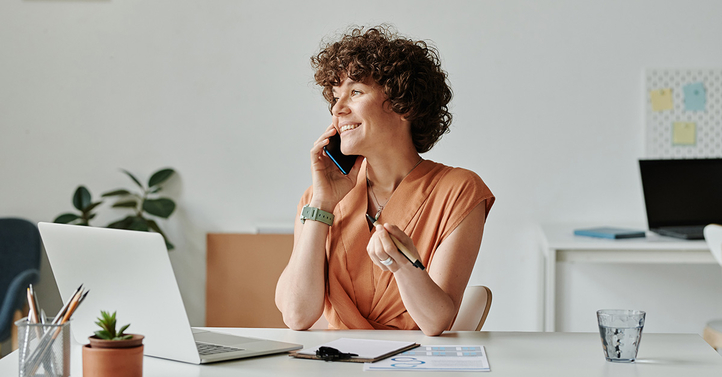 Eine lächelnde Frau telefoniert und notiert in einem modernen Büro, unterstützt durch IT-Support von SHD.