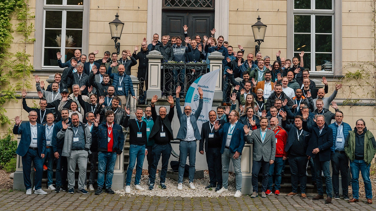 Menschengruppe begrüßt mit Winken, versammelt vor dem SHD, bei einer Networking-Veranstaltung.