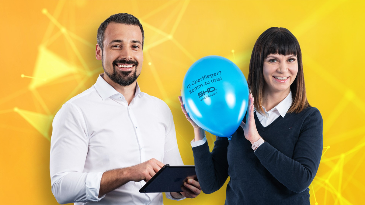 Zwei Mitarbeiter von SHD lächeln, halten ein Tablet und einen blauen Ballon in einem gelben Hintergrund.