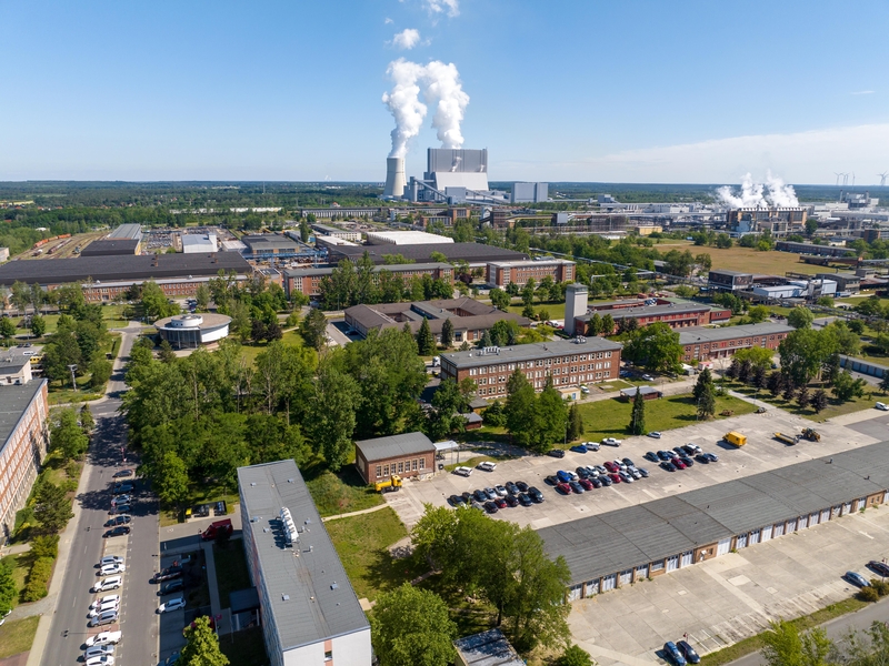 Industriegelände mit Fabriken und Bürogebäuden, bewohnt von Technik und Natur, SHD präsent.