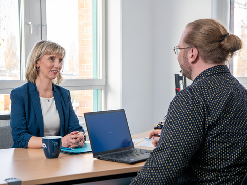 In einem lockeren Job-Interview spricht ein SHD Mitarbeiter mit einer lächelnden Kandidatin.