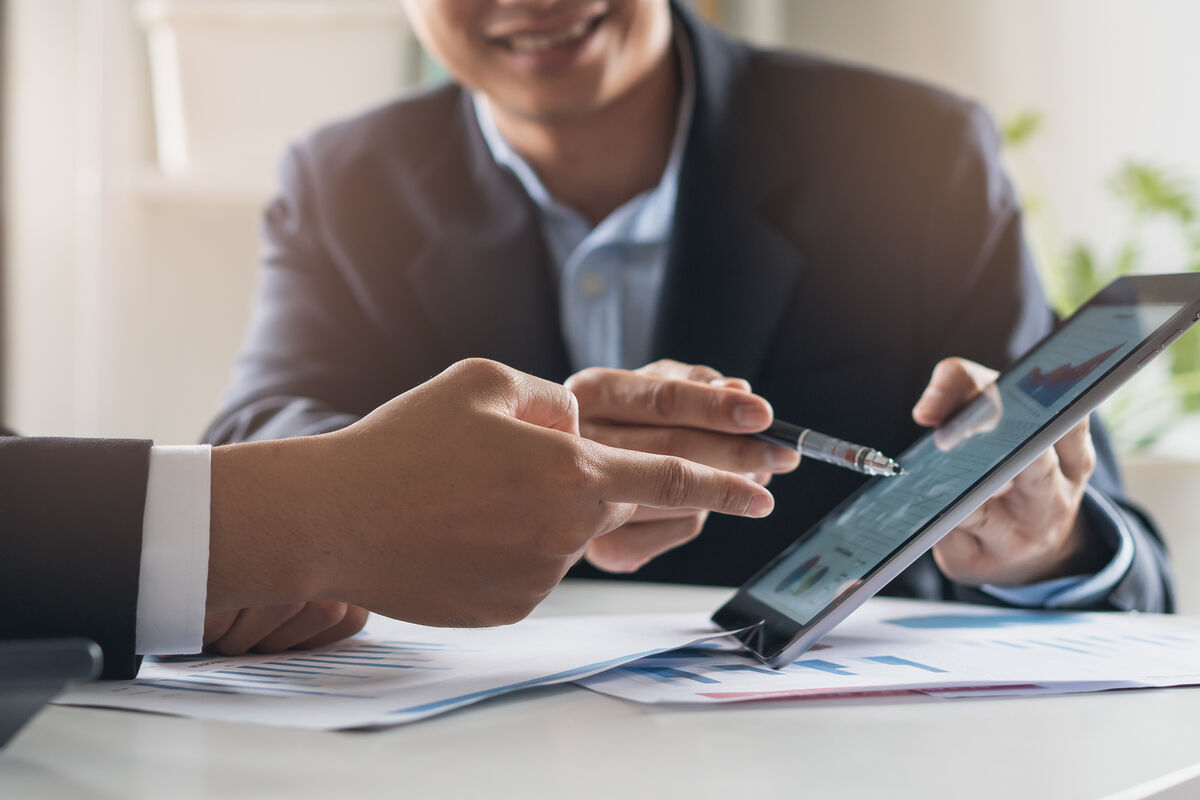 Zwei Geschäftsleute analysieren Daten auf einem Tablet während eines Meetings im Büro. SHD unterstützt digitale Lösungen.