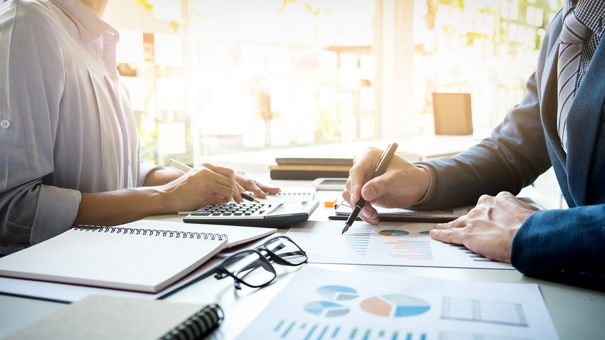 Zwei Personen analysieren gemeinsam Diagramme und Zahlen, unterstützt durch SHD IT-Dienstleistungen.