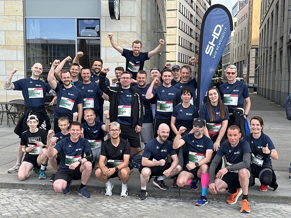 Mitarbeiter von SHD posieren energisch während eines Teamevents in urbaner Umgebung.