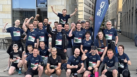 Mitarbeiter von SHD posieren energisch während eines Teamevents in urbaner Umgebung.