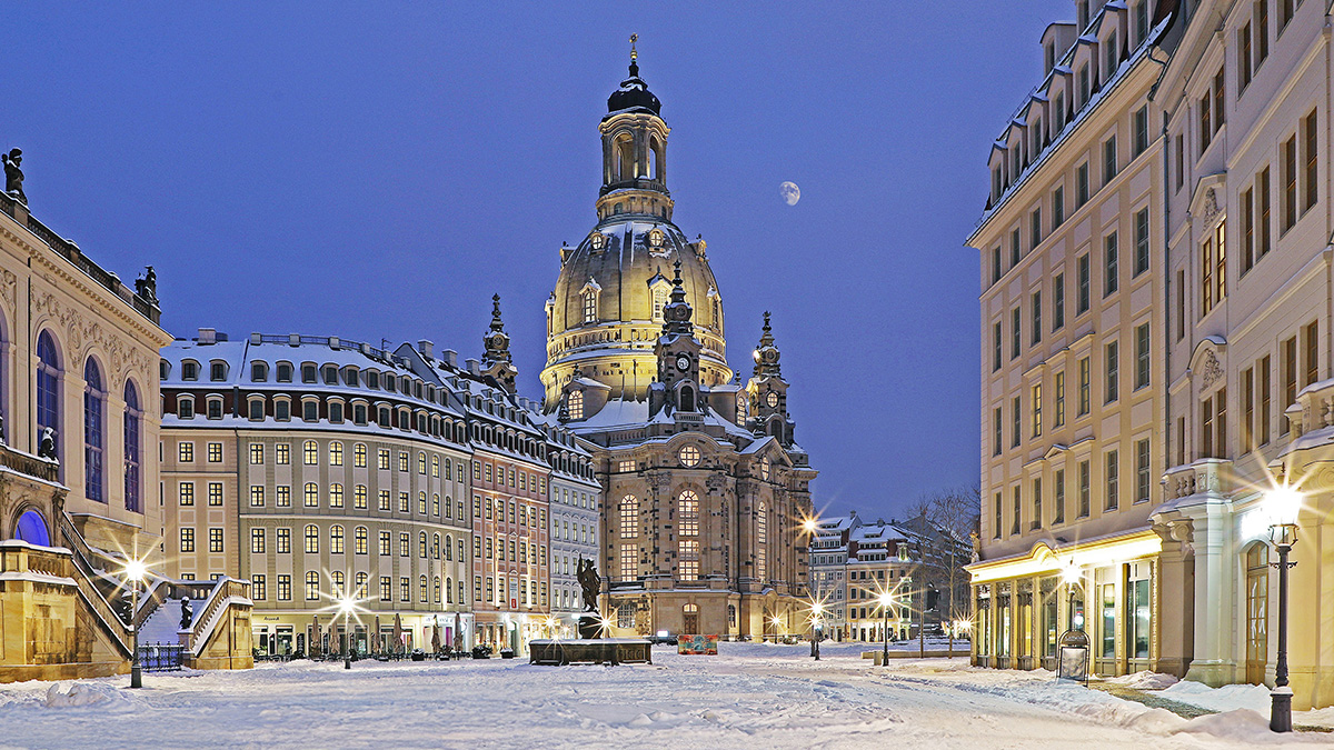 Blick auf die Dresdner Frauenkirche durch eine hell beleuchtete Straße im Winter.