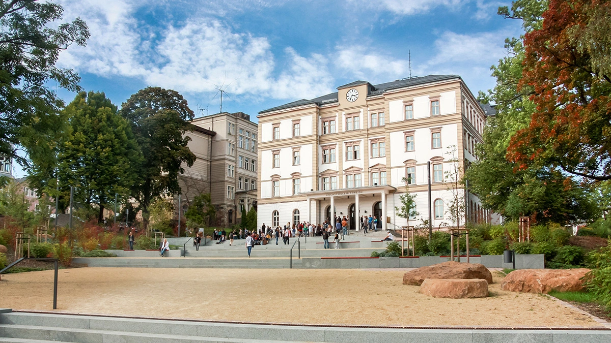 Historisches Gebäude mit Studieninteressierten, umgeben von einer begrünten Umgebung im Herzen der Stadt.