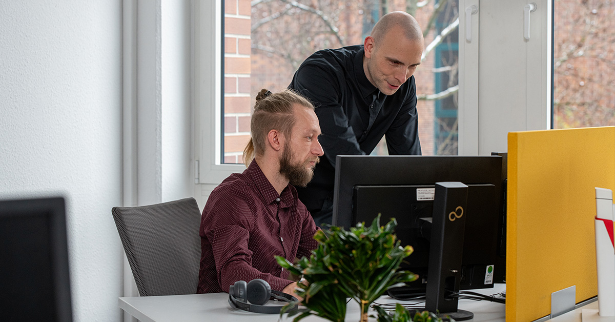 Zwei IT-Fachleute arbeiten gemeinsam an einem Computer im modernen Büro der SHD.